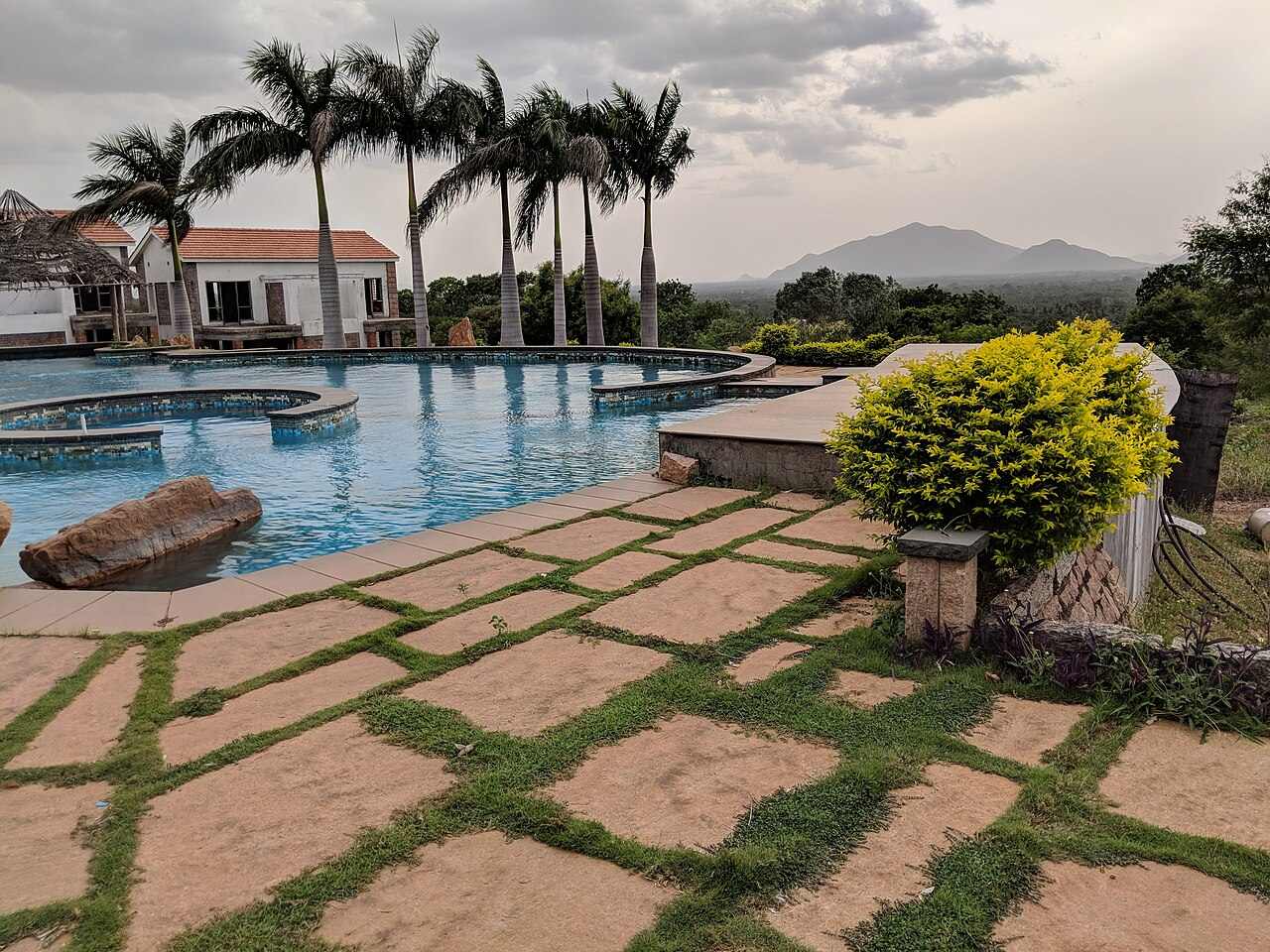 Resort pool with stone deck and hills behind